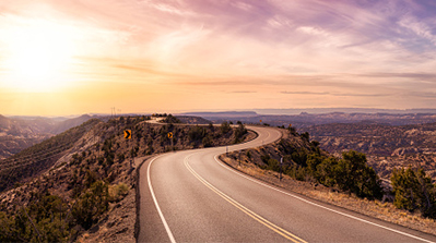 Long, winding highway stretches to the horizon at sunset