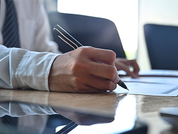 Person writing a note on a desk.