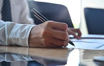 Person writing a note on a desk.