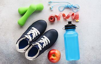 Dumb bells, head phones, measuring tap, running shoes, apple and water bottle.