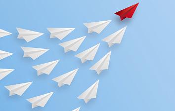 A group of white paper airplanes following a red one.