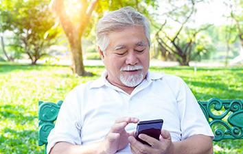 Man looking at phone in a park.