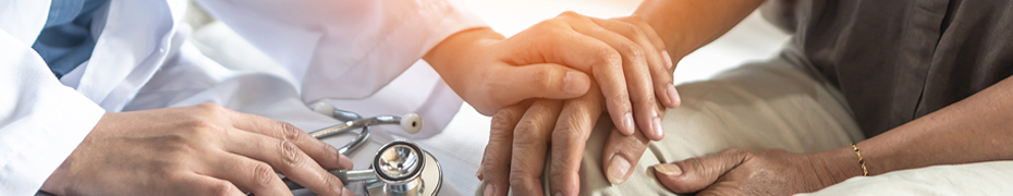 Doctor speaking with patient while holding his hand.